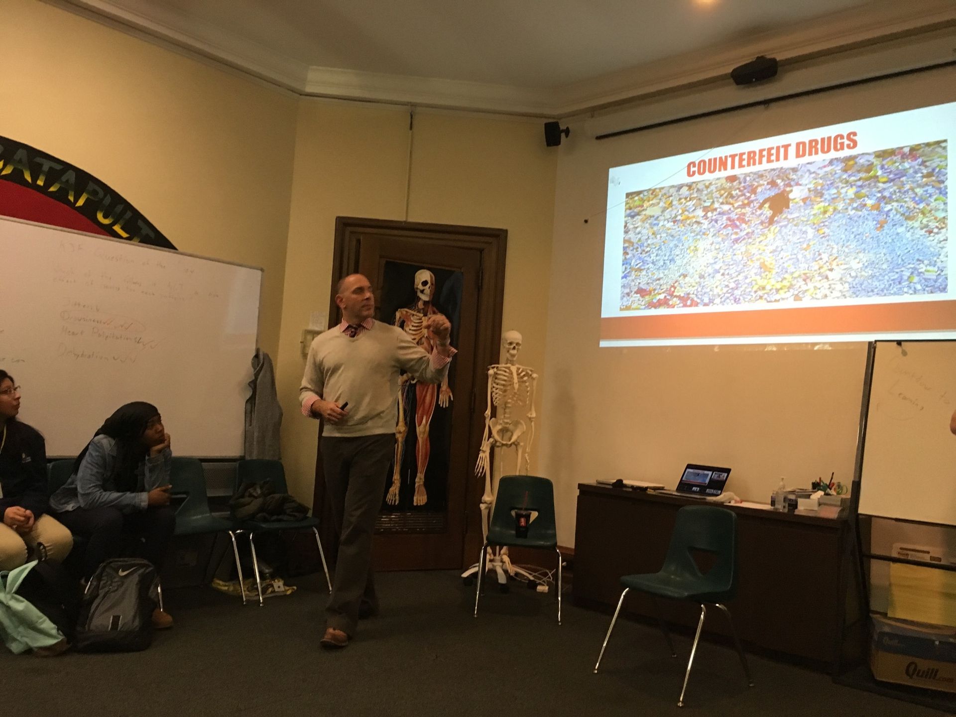 Robb Bassett, Interim Director of the Poison Control Center at Children's Hospital of Philadelphia, shows a PowerPoint slide on counterfeit drugs to students in the Karabots Junior Fellows Program