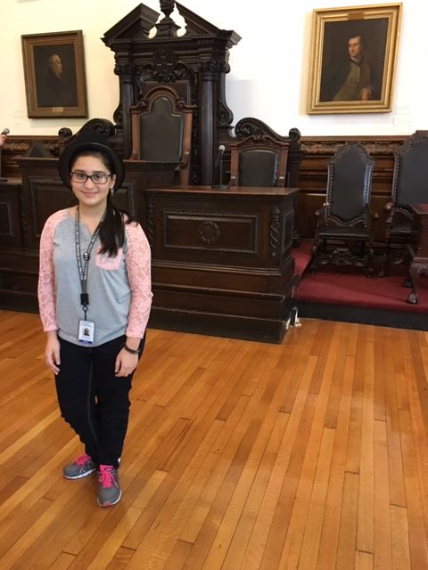 Photo of Viviana, a student in the Karabots Junior Fellows Program, who is wearing a top hat to commemorate her victory in the Project Voice 2016 election.
