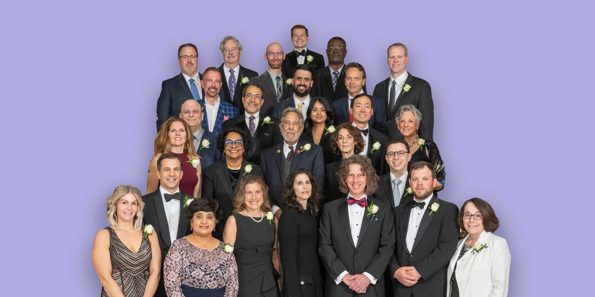 Group of Fellows in black tie attire standing against a light purple background