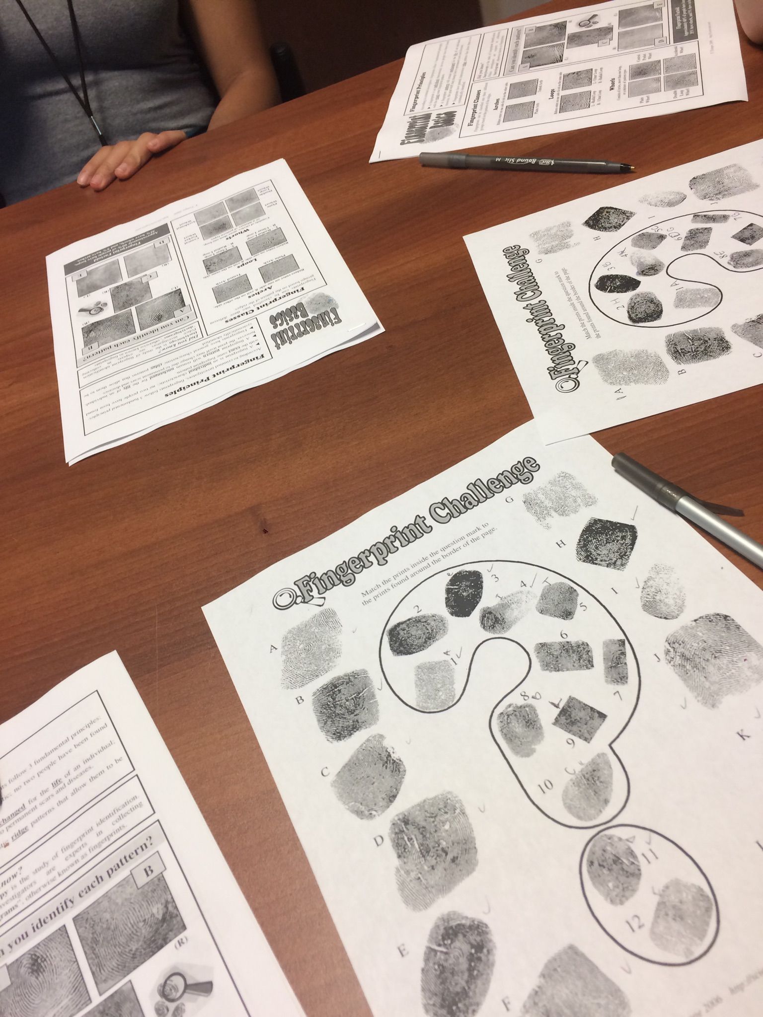 Sheets of fingerprints collected at the Arcadia Crime Scene House are spread across a table.