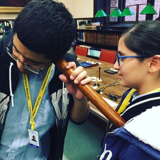 Two students from the Karabots Junior Fellows Program experiment with a Laënnec stethoscope