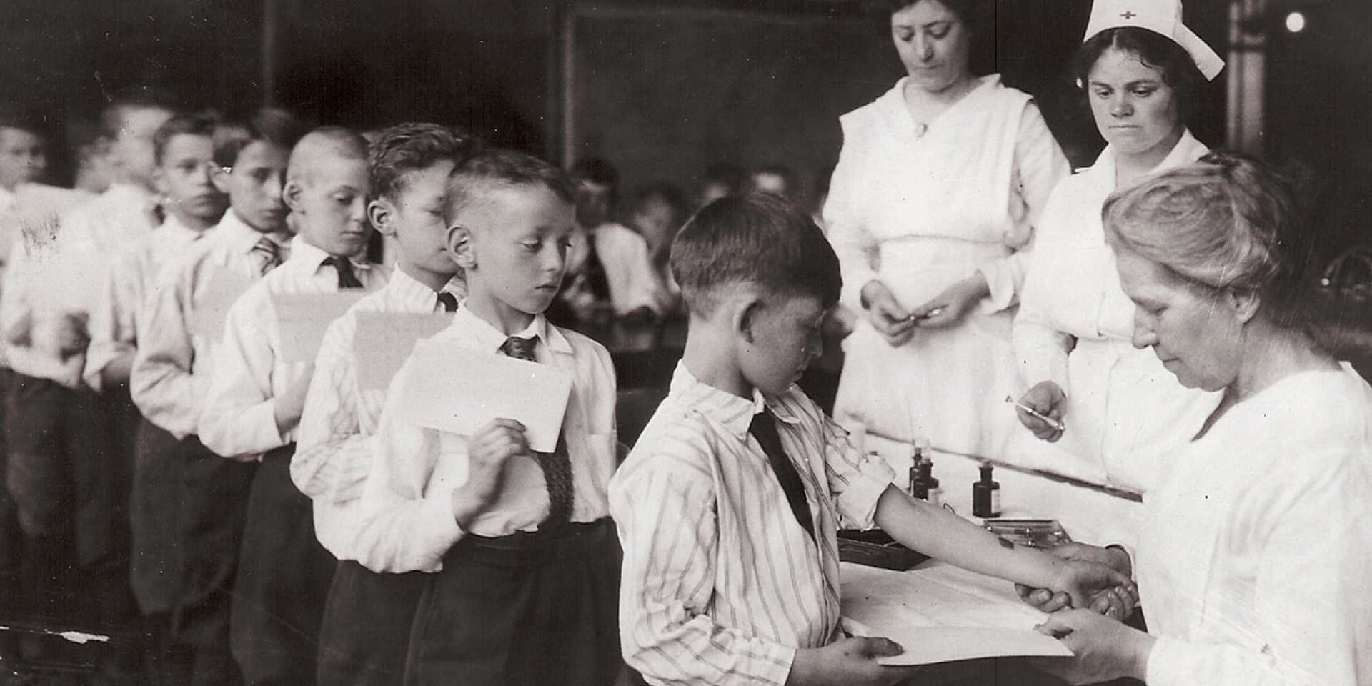 Black and white historical photo of children in line to get vaccines