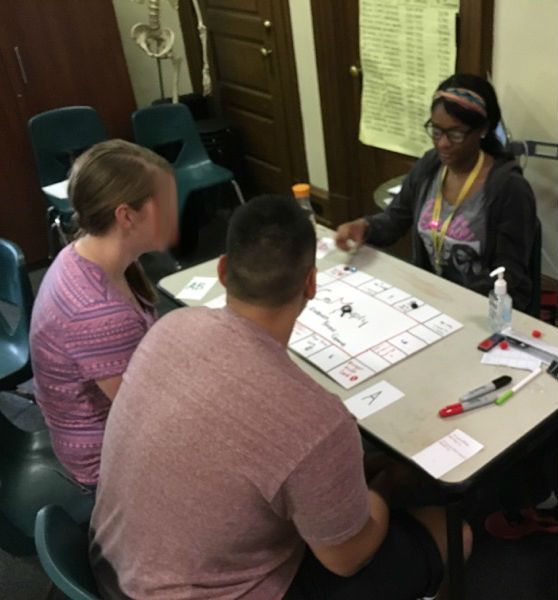 A student in the Karabots Junior Fellows Program demonstrates a board game on forensics to two visitors to the Mütter Museum