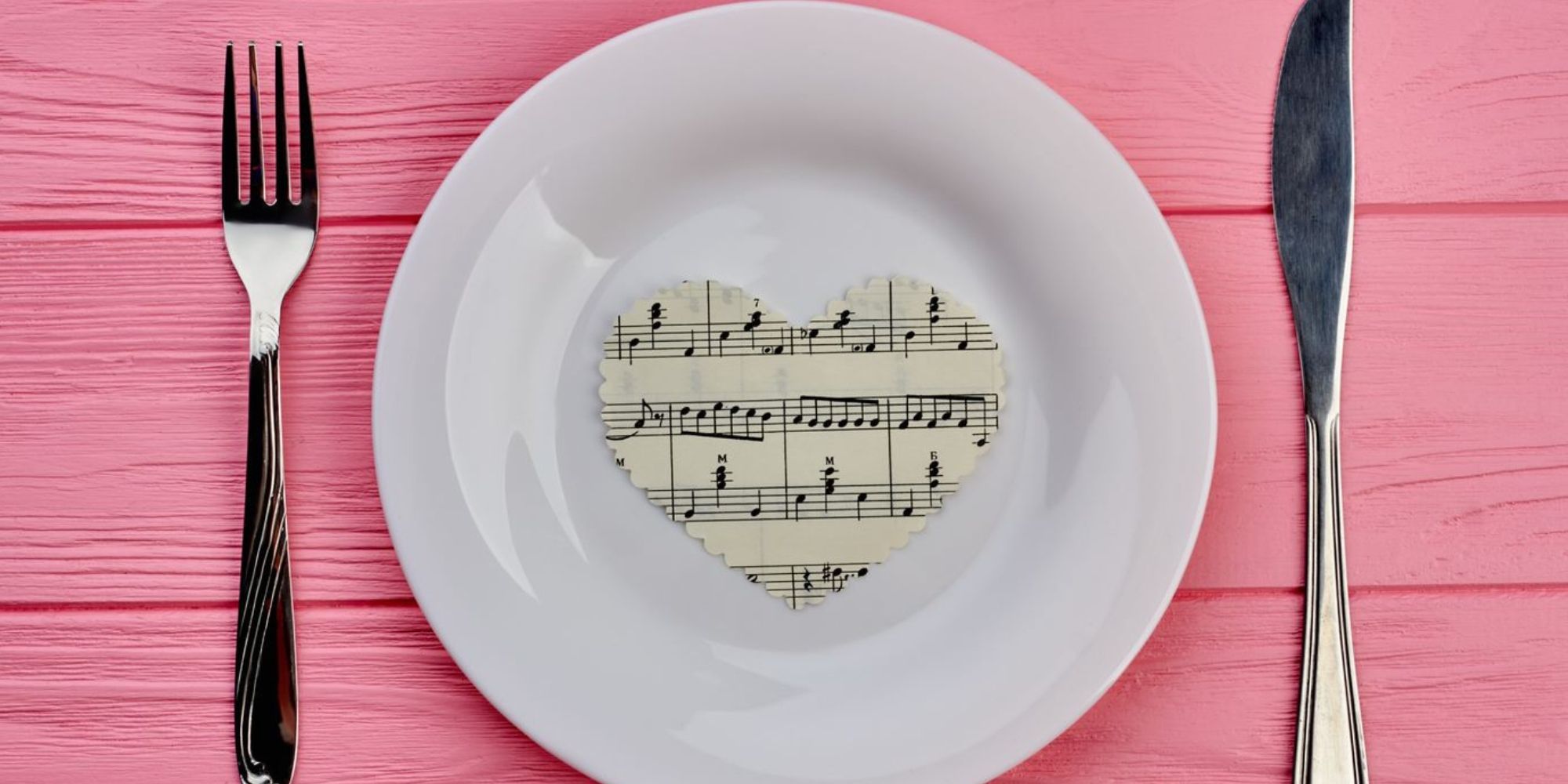 Music for Food Image of White dinner plate with fork and knife, on center of plate is heart with sheet music