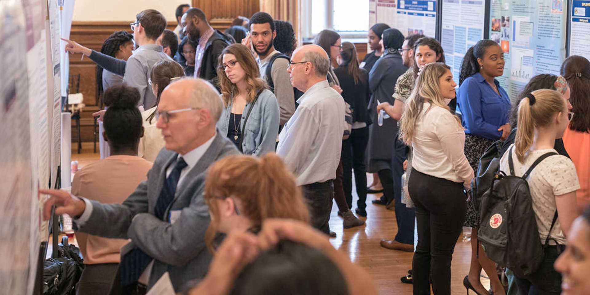 Crowd of people looking at posters displayed in a large room