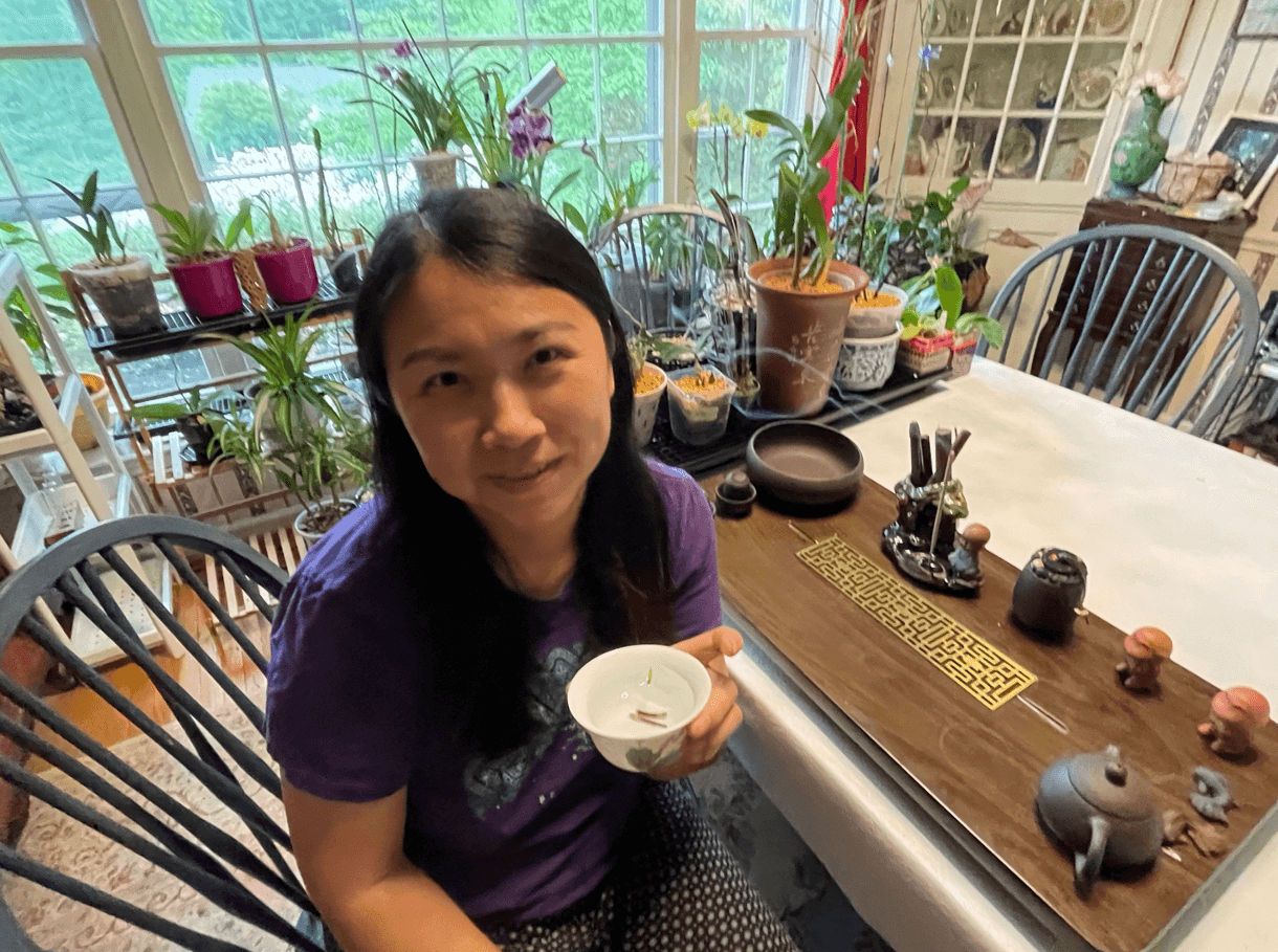 A woman sits holding a cup of Dendrobium tea