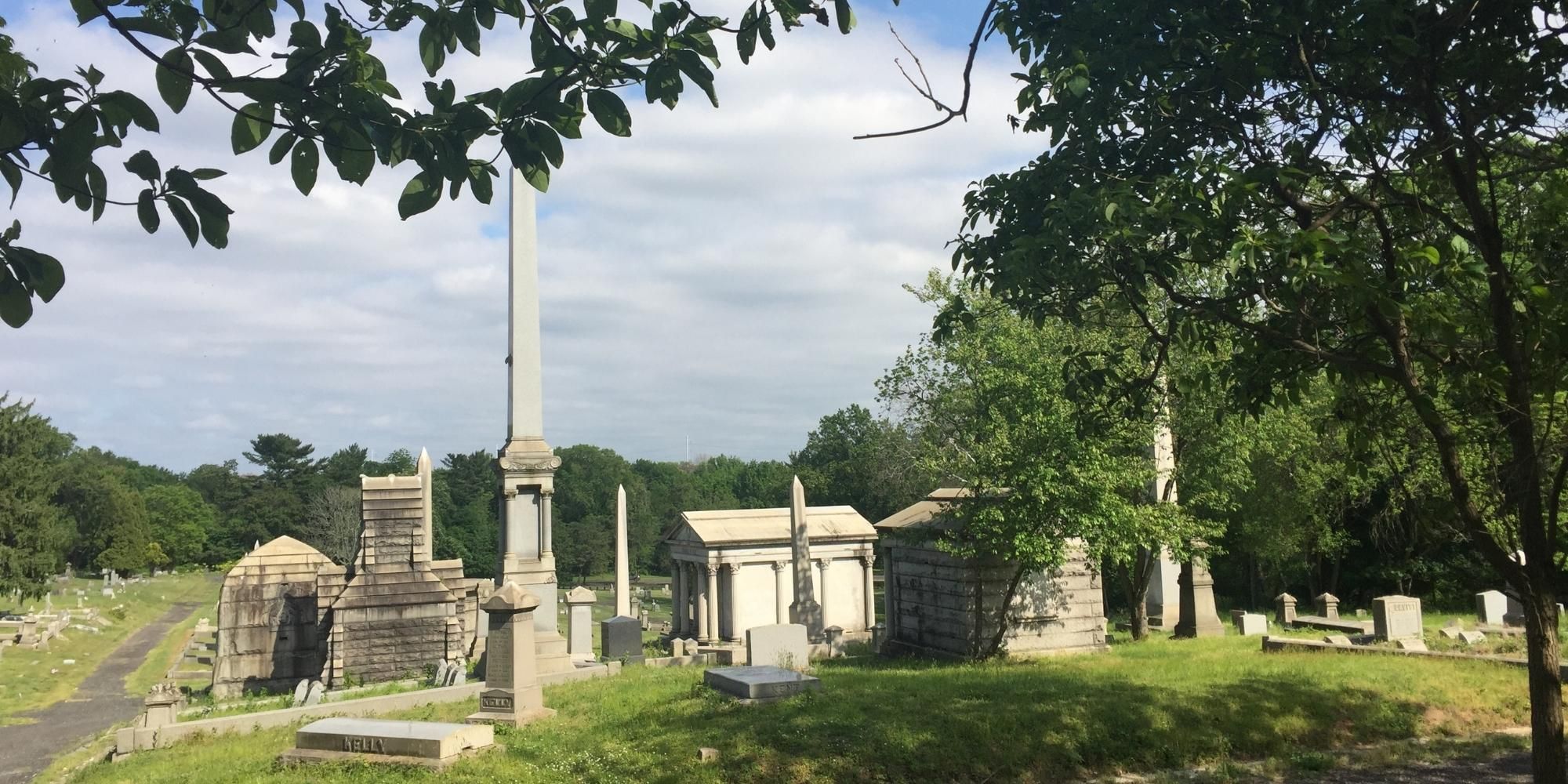 Photo of the grounds and several graves at Mount Moriah cemetery surrounded by grass and green leafed trees