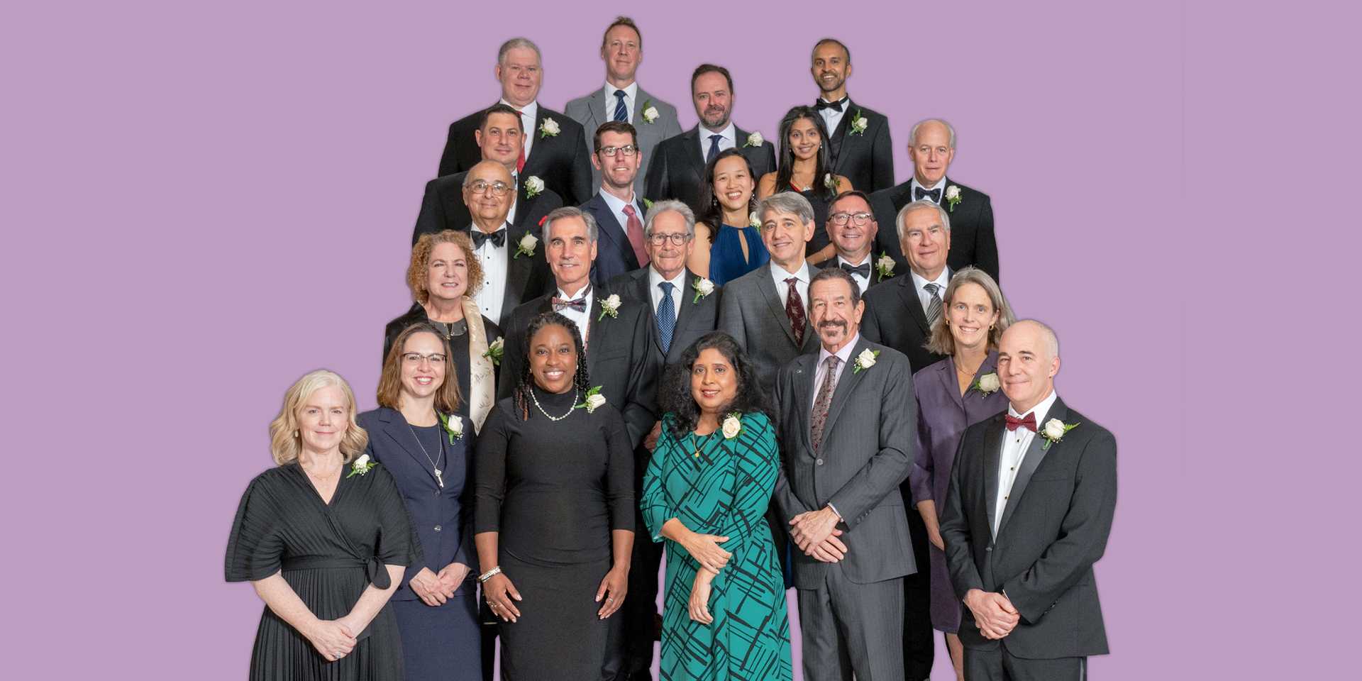 Group of College Fellows in formal dress standing against a purple background