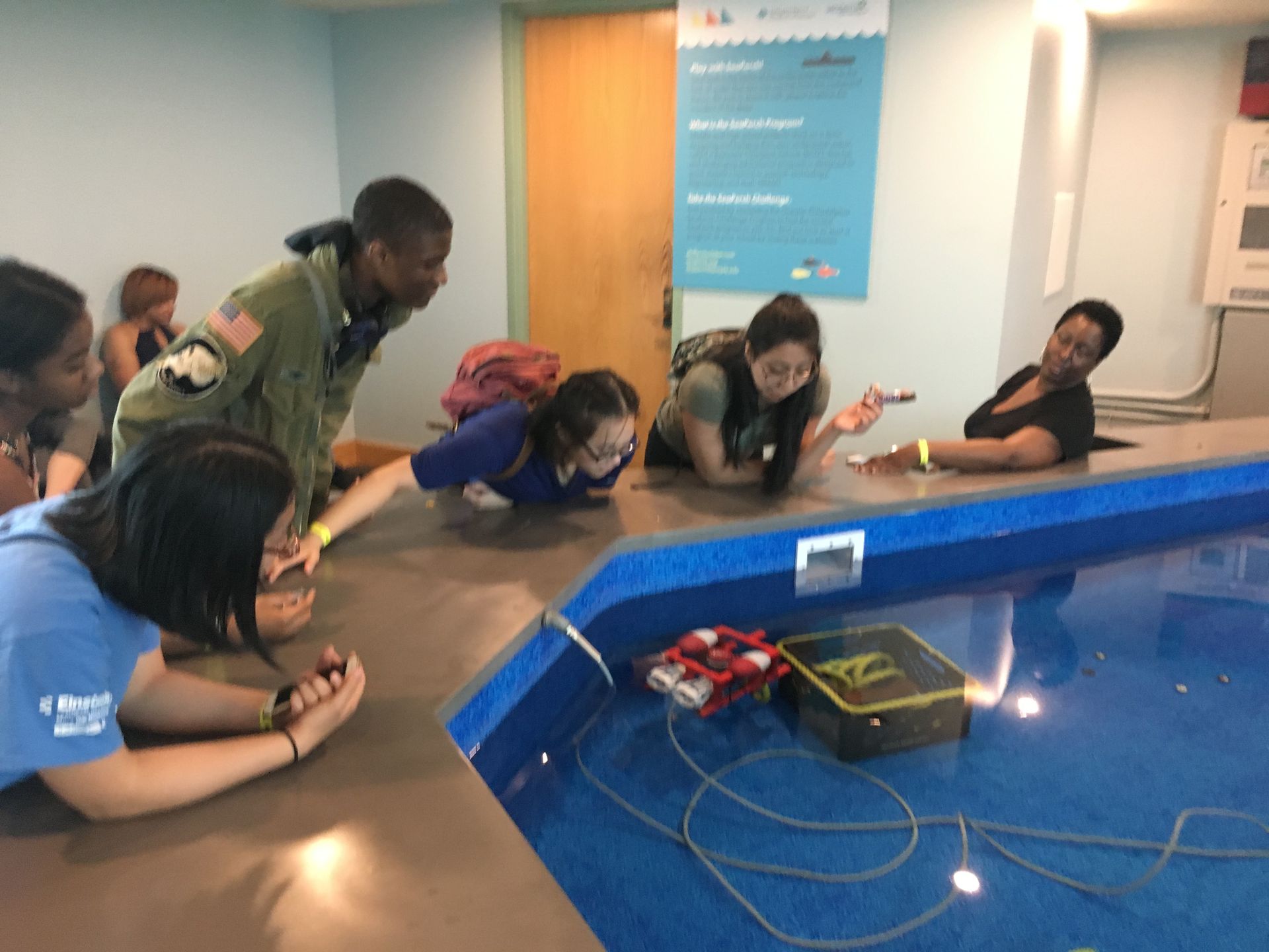 Students in the Karabots Junior Fellows Program pilot a small submarine in a pool in the lobby of the Independence Seaport Museum